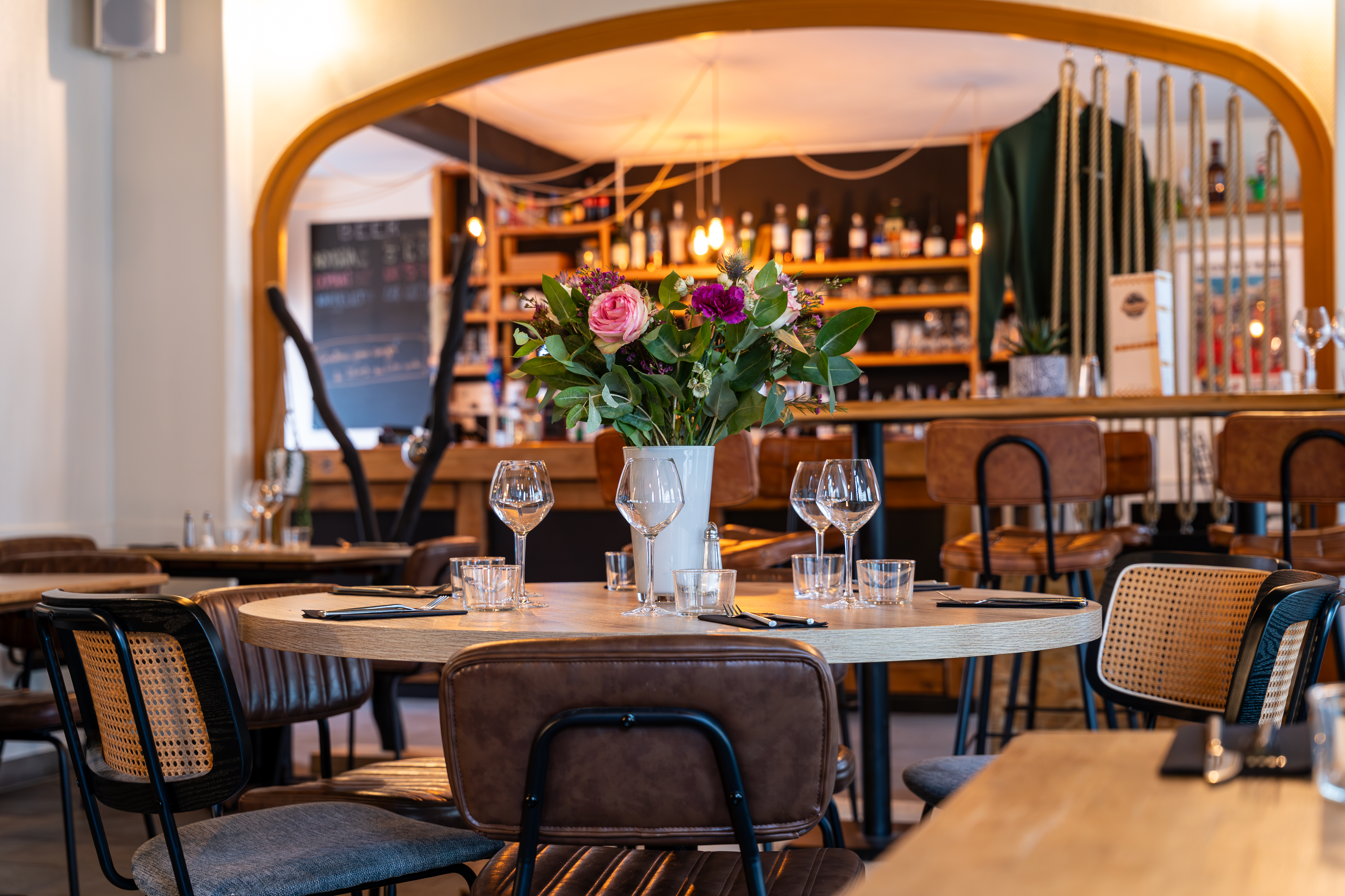 Salle de restaurant conviviale de L'Accalmie avec tables en chêne et fauteuils en rotin